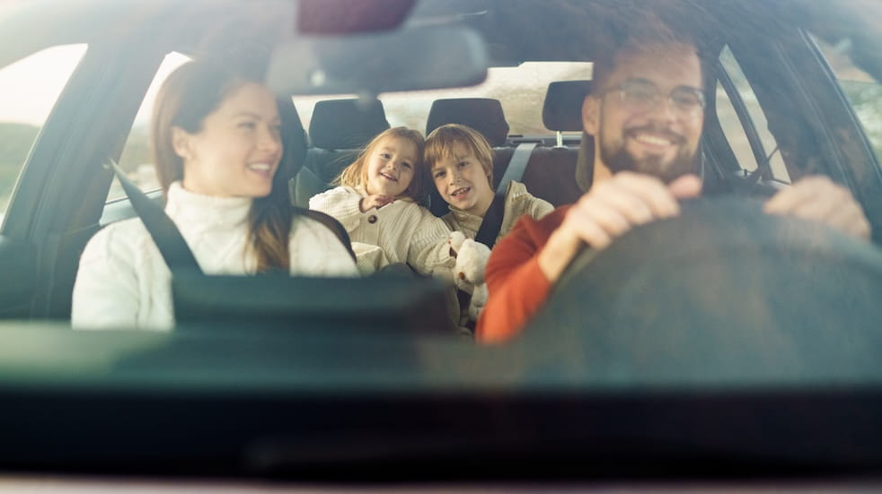 Looking through the windscreen of a car into a happy family of four
